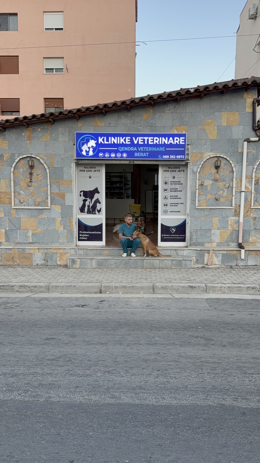 DVM Llazar Sheqi with a dog at the entrance of Qendra Veterinare Berat